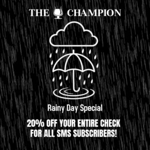 Promotional graphic for The Champion bar showing a white umbrella under a rain cloud with heavy rainfall on a black background, advertising a Rainy Day Special with 20% off the entire check for SMS subscribers and instructions to text JOIN to 1-833-350-0919 to subscribe.